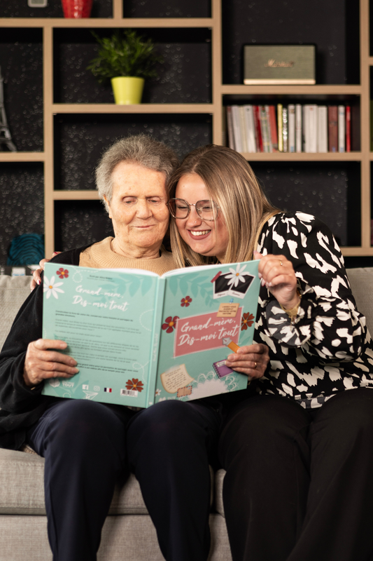 Une grand-mère et sa petite-fille qui sont entrain de lire le livre 'Grand-mère, Dis-moi tout".