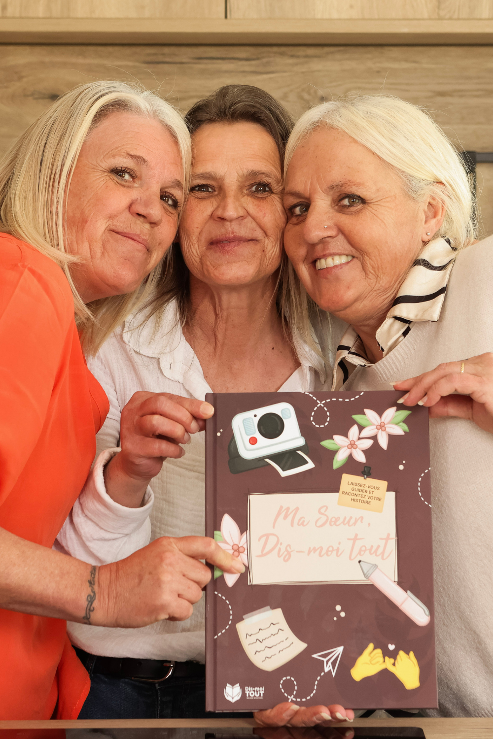 trois soeurs souriantes avec le livre Ma soeur, dis-moi tout dans les mains