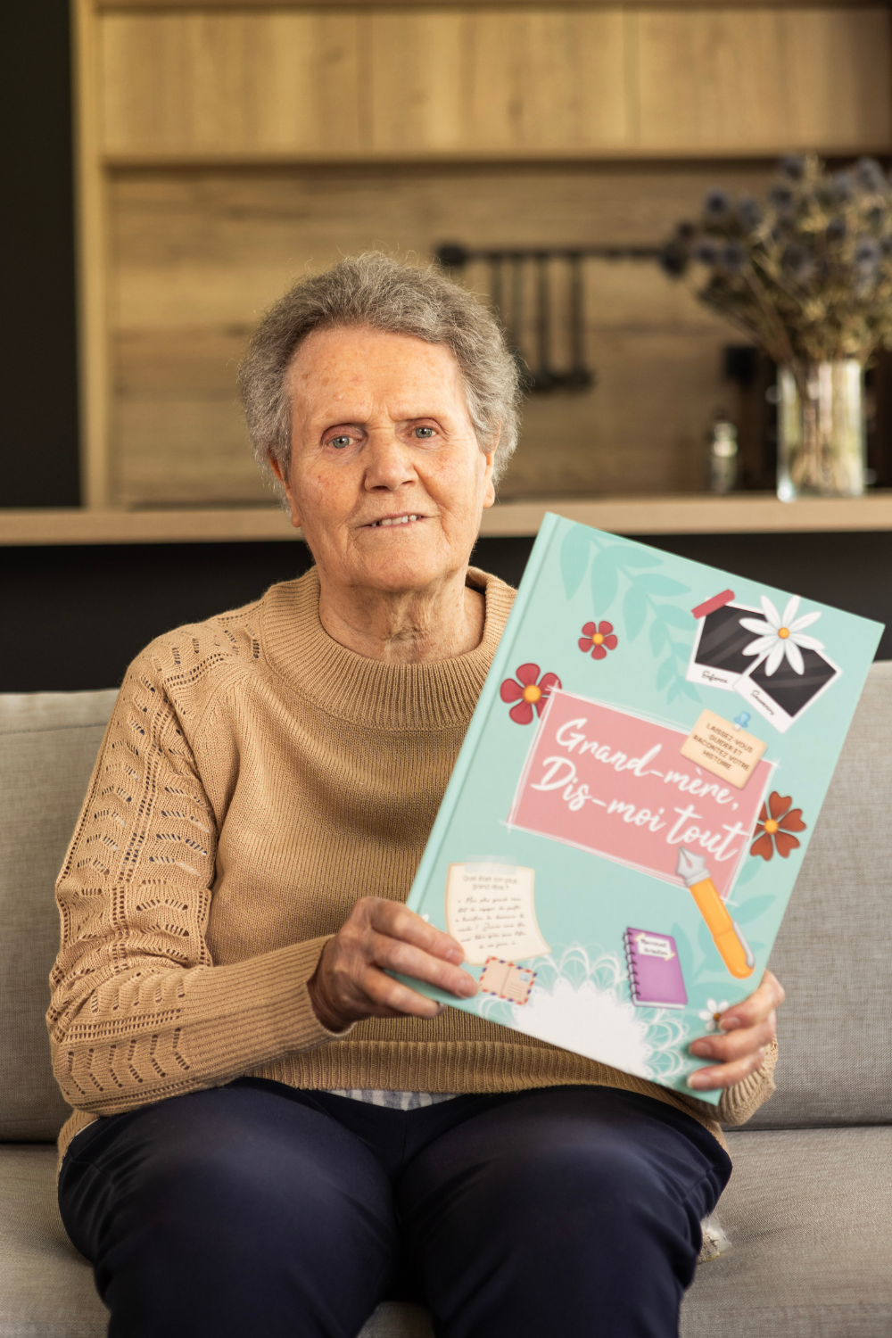 Une grand-mère tient dans les mains le livre "Grand-mère, Dis-moi tout.