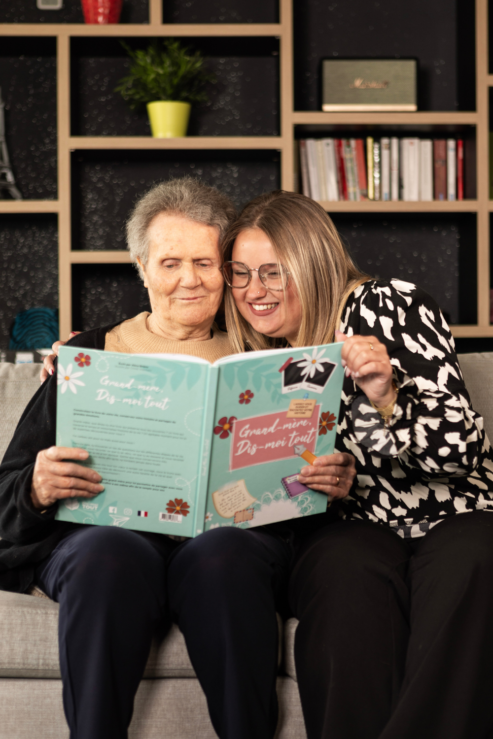 Une grand-mère et sa petite-fille qui sont entrain de lire le livre 'Grand-mère, Dis-moi tout".