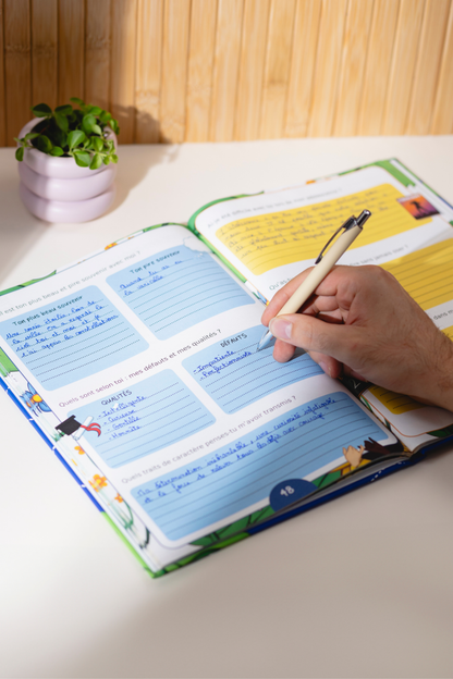 Photo du livre Dis-moi tout ouvert avec une main qui est entrain d'écrire dedans