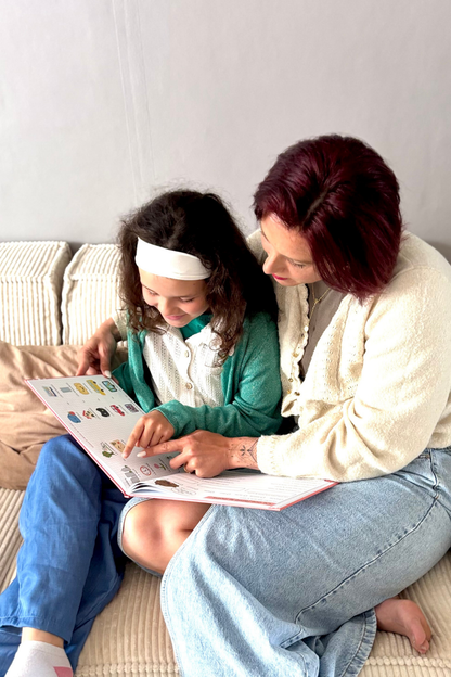 Une maman et sa fille sont sur leur canapé et elles regardent le livre "Maman, je vous dis tout"
