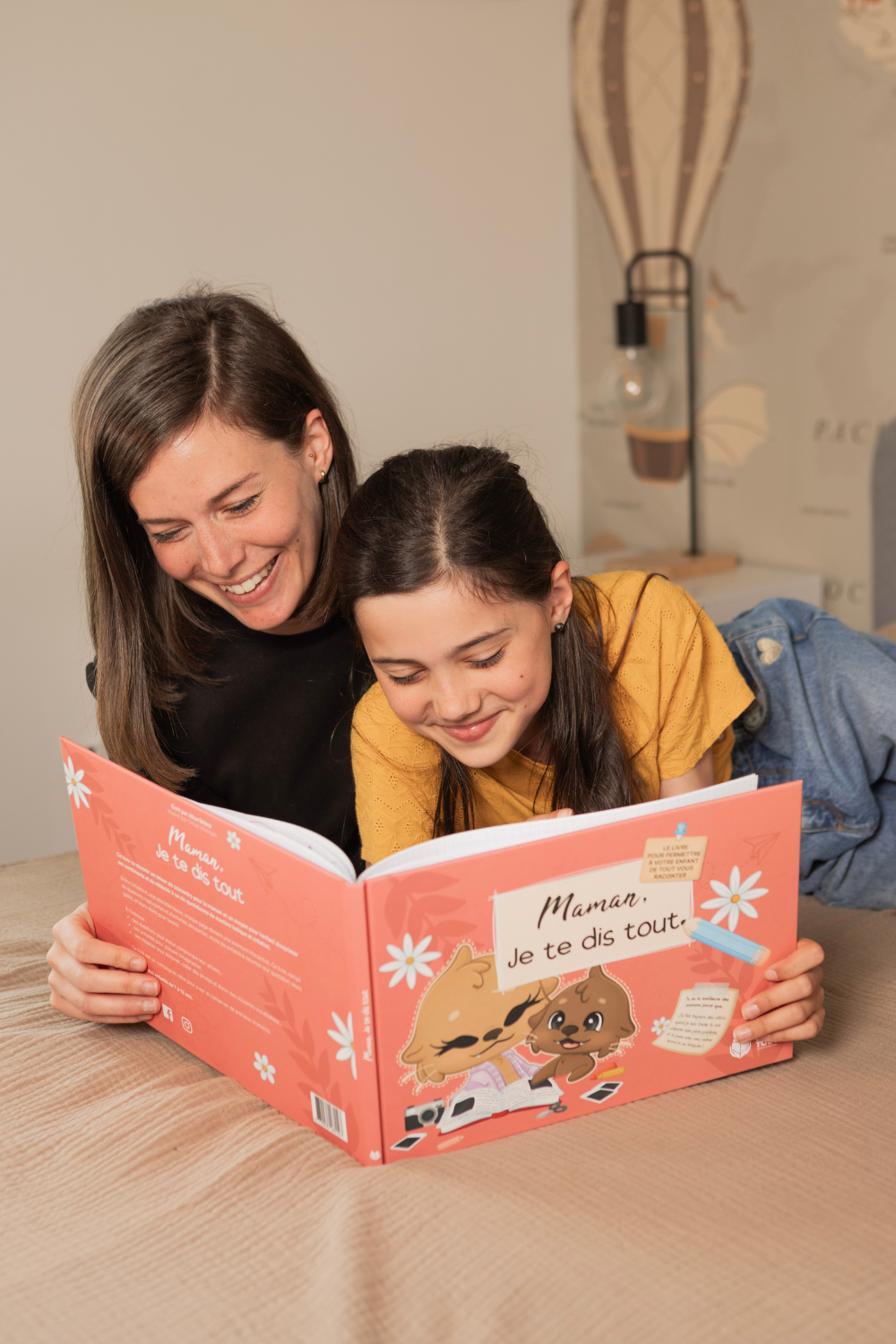 Une fille et sa mère sont entrain de lire le livre "Maman, Je te dis tout"