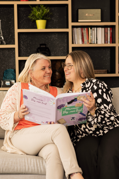Deux femmes se regardent en souriant en tenant le livre "Marraine, Dis-moi tout" entre leurs mains