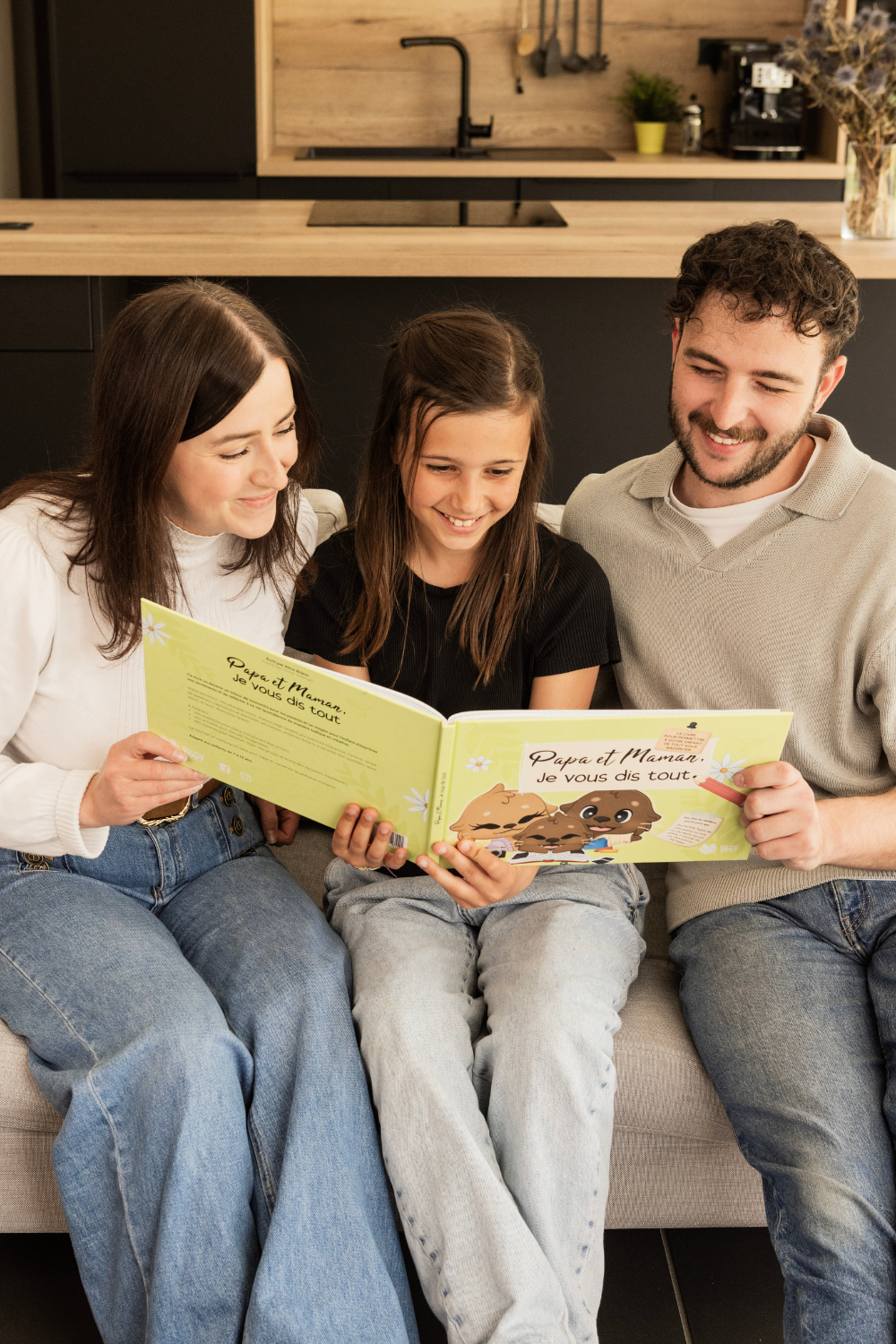 Une fille et ses parents sont entrain de lire le livre "Papa et Maman, Je vous dis tout"